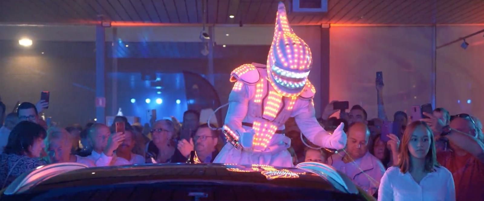 Un artiste en costume lumineux divertit la foule lors d'un événement de KIA Steveny